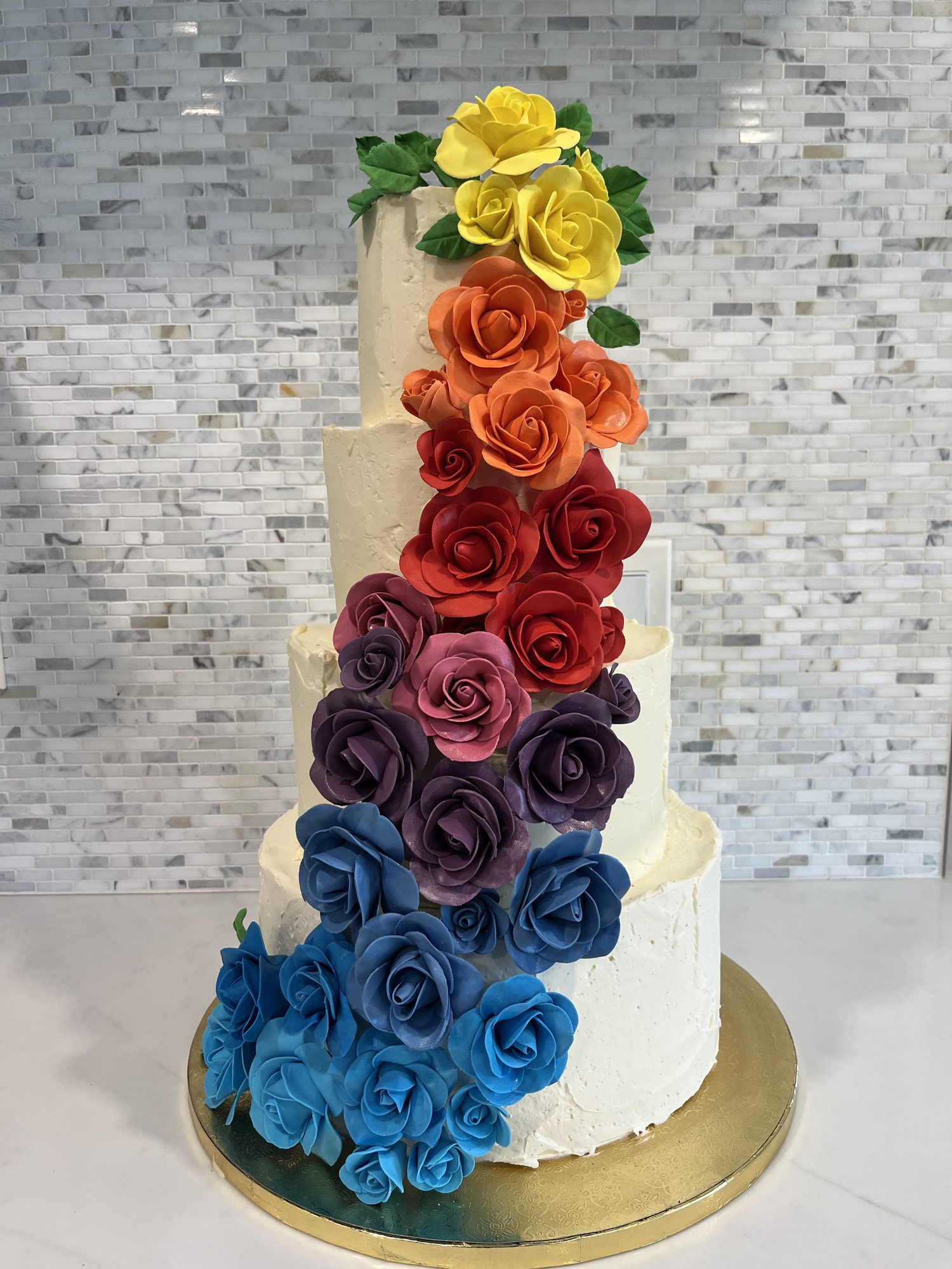 Wedding cake with a cascade of rainbow sugar roses